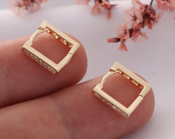 May include: A pair of gold square hoop earrings with clear cubic zirconia stones.