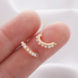 May include: A pair of gold hoop earrings with a row of small white pearls around the hoop.