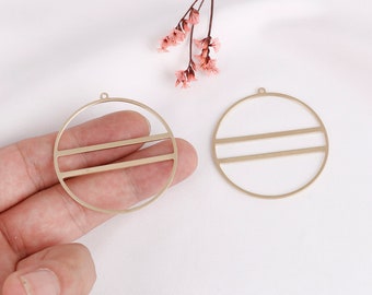 May include: Two gold-toned metal circle pendant charms with a double line design. The charms have a hole at the top for attaching to jewelry.