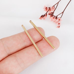 May include: Two gold-colored metal bar earrings with a loop at the top.