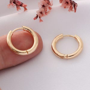 May include: A pair of gold hoop earrings. The earrings are simple and classic, with a smooth, polished finish.