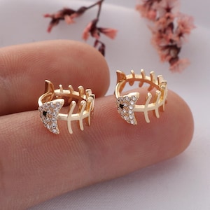 May include: A pair of gold-tone fishbone earrings with clear and black cubic zirconia stones.