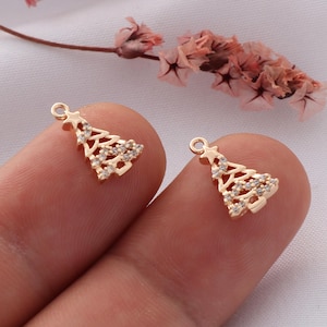 May include: Two gold-tone Christmas tree charms with clear rhinestones. The charms are small and delicate, perfect for adding a touch of holiday sparkle to jewelry or crafts.