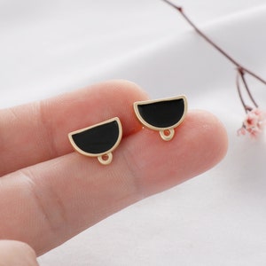 May include: Two gold-toned half-circle charms with black enamel. Each charm has a small loop at the bottom.