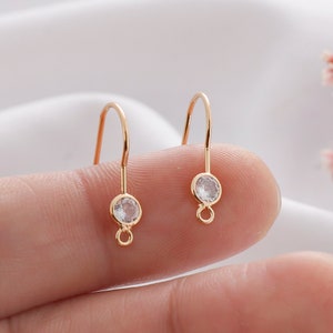 May include: A pair of gold-tone earring hooks with clear round crystal accents.