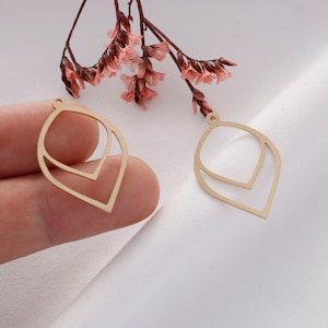 May include: Two gold-colored metal leaf-shaped earring blanks with a double-layered design.