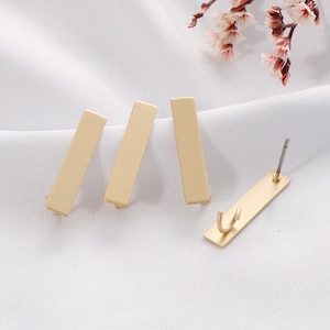 May include: Four gold-coloured rectangular bar earrings. The earrings are simple and minimalist in design.
