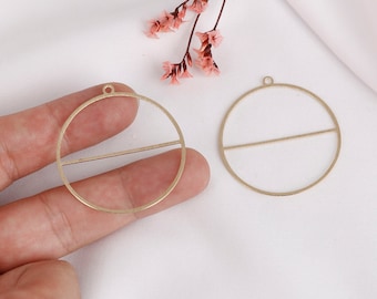 May include: Two gold-toned metal circle pendant frames with a horizontal bar across the center. The frames are perfect for adding resin, glass, or other embellishments.