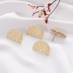 May include: Three gold-toned metal earring blanks with a textured surface. The blanks are in the shape of a half circle and have a small hole at the top.