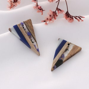 May include: Two triangular resin and wood pendants with blue, white, and gold accents. The pendants have a layered look with wood, resin, and gold flakes.