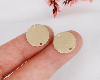 May include: Two gold-colored metal circles with two holes each. The circles have a brushed finish.