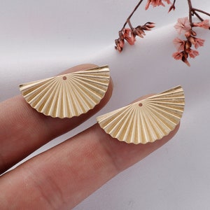 May include: Two gold-colored metal fan-shaped earring charms with a small hole at the top.