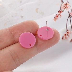 May include: A pair of pink round stud earrings with a silver post.