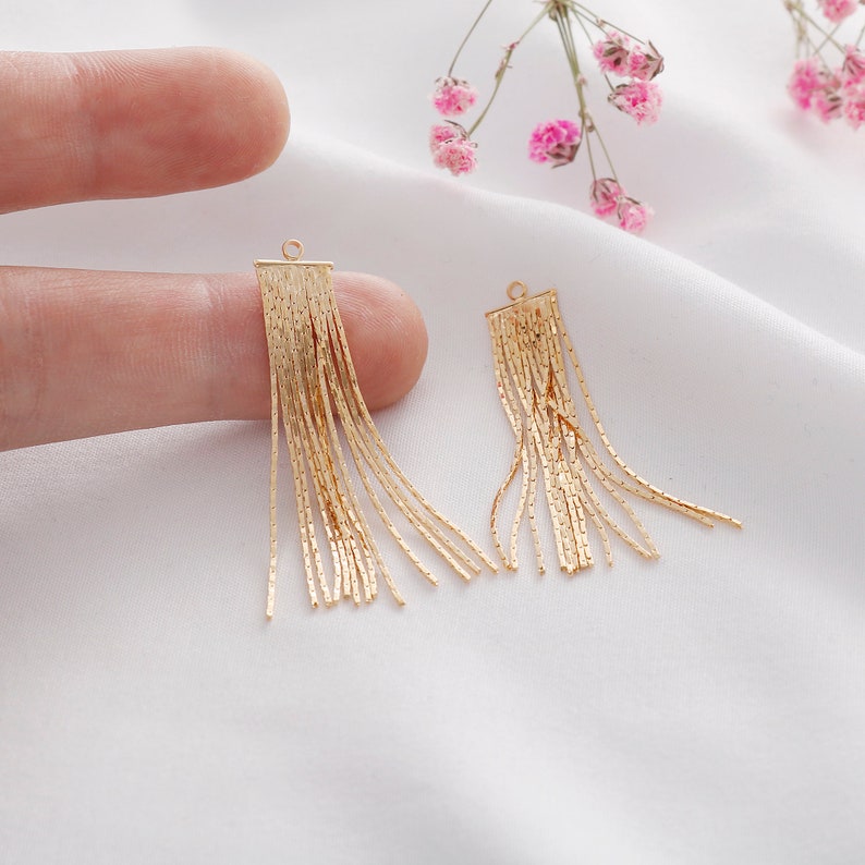 May include: Two gold-toned tassel earrings with a rectangular top and multiple strands of chain hanging down.