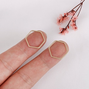May include: Two gold hexagon shaped rings, one on each finger.