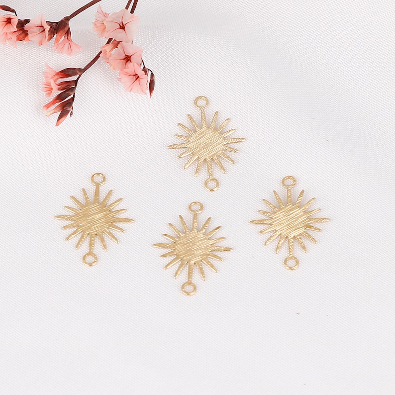 May include: Four gold-toned metal starburst charms with a textured surface and two jump rings on each charm.