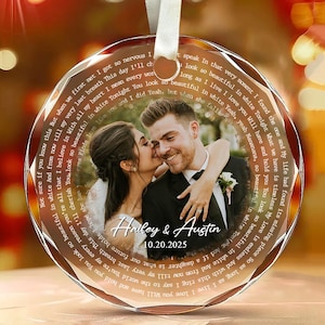 May include: A round glass ornament featuring a photograph of a couple embracing. The text "Haley & Austin" and "10.20.2025" is printed in the center, surrounded by a circular border of song lyrics. A white ribbon is attached to the top.