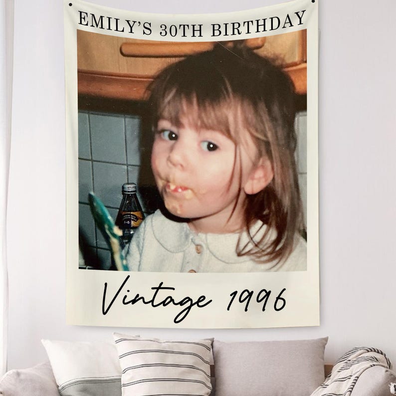 May include: A cream-colored wall tapestry featuring a vintage photo of a young person. The text "EMILY'S 30TH BIRTHDAY" is at the top, with "Vintage 1996" at the bottom. The photo shows a person with food on their face.