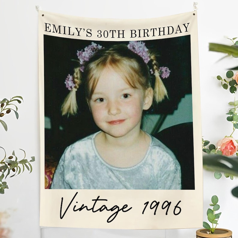 May include: A beige wall hanging featuring a vintage photo of a young girl with blonde pigtails and floral hair accessories. The text "EMILY'S 30TH BIRTHDAY" is at the top, and "Vintage 1996" is at the bottom.