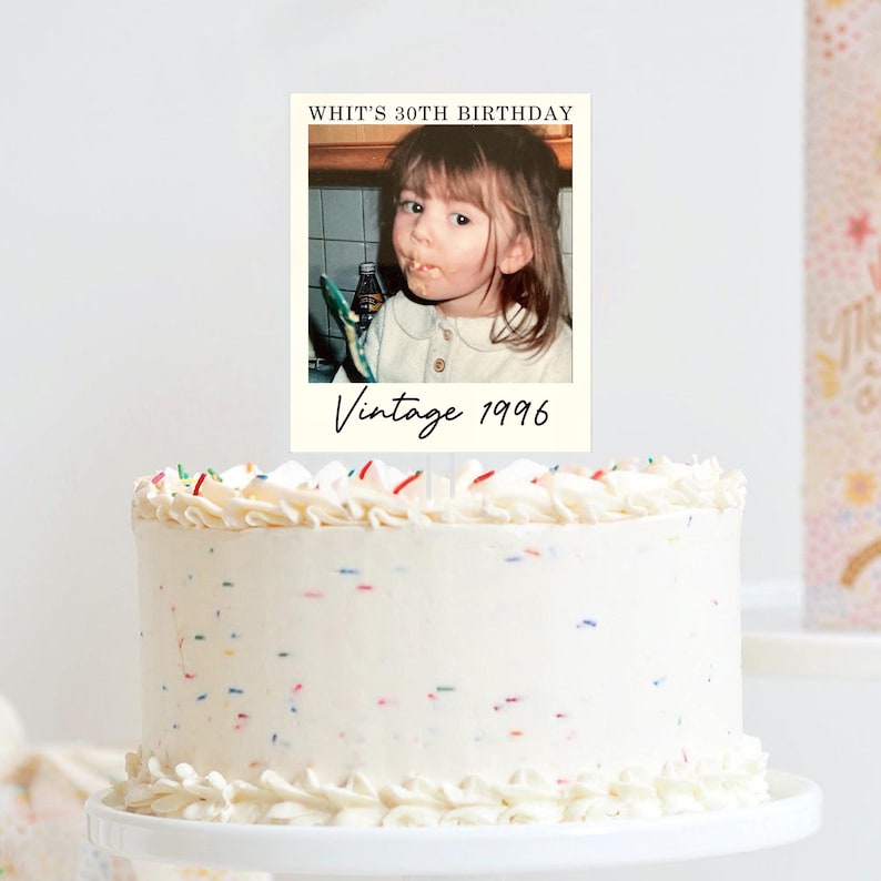 K&ouml;nnte beinhalten: Ein runder wei&szlig;er Kuchen mit bunten Streuseln, gekr&ouml;nt von einer rechteckigen Karte mit dem Foto eines kleinen Kindes. Der Text auf der Karte lautet oben WHIT'S 30TH BIRTHDAY und unten Vintage 1996 in einer schwarzen Schreibschrift.