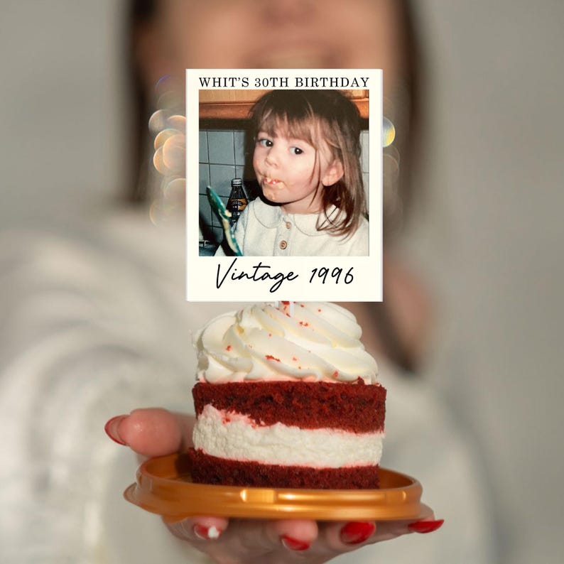 K&ouml;nnte beinhalten: Ein kleiner Red-Velvet-Kuchen mit wei&szlig;em Zuckerguss auf einem goldenen Teller, gekr&ouml;nt von einer rechteckigen Karte mit dem Foto eines kleinen Kindes und dem Text "WHIT'S 30TH BIRTHDAY" oben und "Vintage 1996" in Schreibschrift unten.