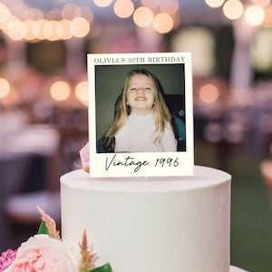 K&ouml;nnte beinhalten: Ein rechteckiger Tortenaufleger mit wei&szlig;em Rand und einem zentralen Foto eines jungen Kindes mit langem blonden Haar. Der Text OLIVIA'S 30TH BIRTHDAY ist oben in Schwarz gedruckt und Vintage 1996 ist darunter in schwarzer Schreibschrift zu sehen.