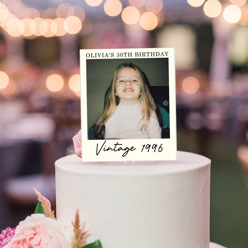 K&ouml;nnte beinhalten: Ein rechteckiger Tortenaufleger mit wei&szlig;em Rand und einem zentralen Foto eines jungen Kindes mit langem blonden Haar. Der Text OLIVIA'S 30TH BIRTHDAY ist oben in Schwarz gedruckt und Vintage 1996 ist darunter in schwarzer Schreibschrift zu sehen.