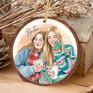 May include: A wooden ornament with a watercolor illustration of two smiling people holding coffee cups. The word "Bestie" is written above the image. The ornament has a gold string for hanging and a natural wood grain edge.