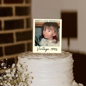 K&ouml;nnte beinhalten: Ein rechteckiger Tortenaufleger mit einem Foto eines Kindes, dem Text "WHIT'S 30TH BIRTHDAY" oben und "Vintage 1996" in Schreibschrift unten. Der Aufleger befindet sich auf einer wei&szlig; glasierten Torte mit einer strukturierten Oberfl&auml;che.