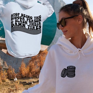 May include: White hoodie with a drawstring hood and a tire graphic on the front. The back of the hoodie features the text "STOP BEING THE BIGGER PERSON & SLASH THEIR DAMN TIRES" above a tire track design.