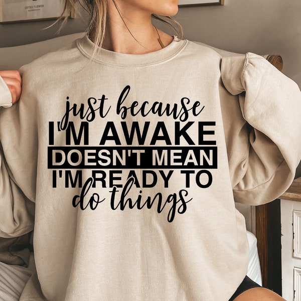 Könnte beinhalten: Ein beiger Pullover mit schwarzem Text, der "just because I'M AWAKE DOESN'T MEAN I'M READY TO do things" lautet.