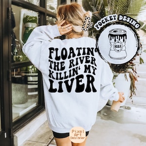 May include: White sweatshirt with black text that reads "Floating the river killin' my liver". The sweatshirt has a pocket on the front with a black and white illustration of a can of beer.