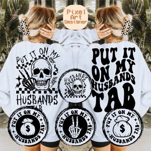 May include: White sweatshirt with black text that reads "Put it on my husbands tab". The text is in a retro font. There are four smaller black and white graphics with the same text in a circle around the main text.