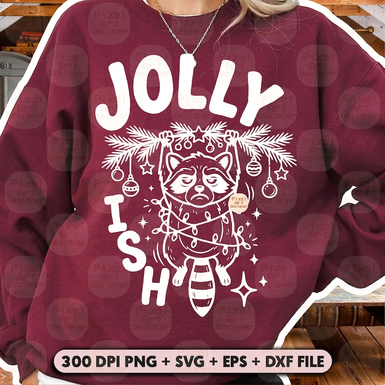 May include: A maroon crewneck sweatshirt featuring a white graphic of a raccoon hanging from a pine branch decorated with ornaments and string lights. The text JOLLY ISH is printed in large white letters above and beside the raccoon illustration.