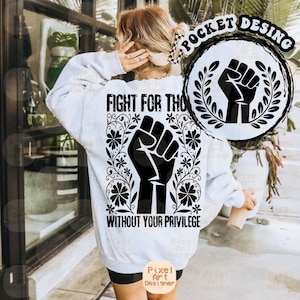 May include: White sweatshirt with a black graphic of a raised fist surrounded by floral elements. The text "FIGHT FOR THO" and "WITHOUT YOUR PRIVILEGE" are printed on the back. A circular design with a fist is on the upper right.