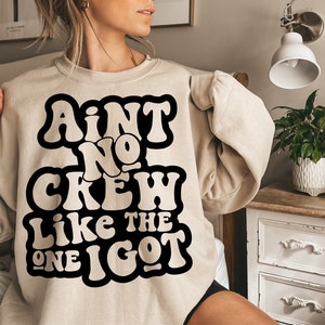 May include: A beige sweatshirt with a black graphic that reads "Ain't No Crew Like The One I Got" in a retro font.