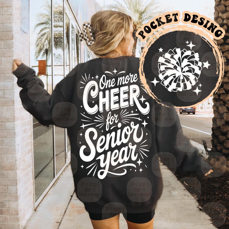 May include: Dark gray sweatshirt with the text "One more CHEER for Senior year" in white. A circular graphic with a white pom-pom and stars is on the upper right. The sweatshirt is a casual style.
