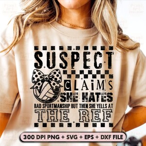 Könnte beinhalten: Beiges T-Shirt mit einem schwarz-weißen Grafikdesign. Die Grafik zeigt den Text "SUSPECT CLAIMS SHE HATES BAD SPORTSMANSHIP BUT THEN SHE YELLS AT THE REF" und einen Volleyball mit einer Schleife. Der untere Teil des Shirts hat den Text "300 DPI PNG + SVG + EPS + DXF FILE".