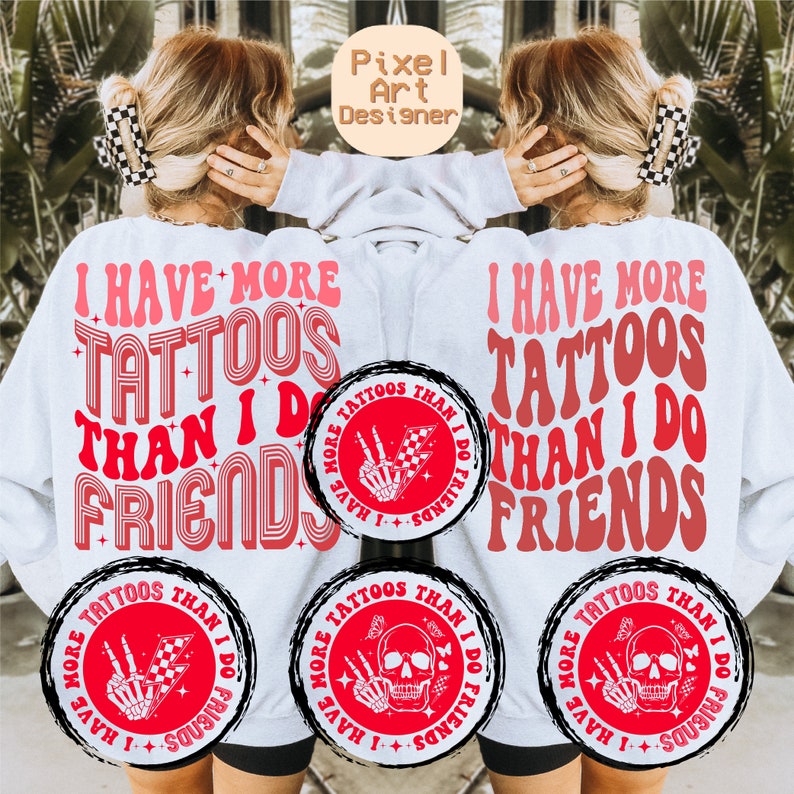 May include: White sweatshirt with red text that reads "I have more tattoos than I do friends". The text is in a retro font style. There are three red circles with black outlines on the sweatshirt. Each circle has a black and white illustration of a skeleton hand with a peace sign and a checkered flag. The text in the circles reads "I have more tattoos than I do friends".