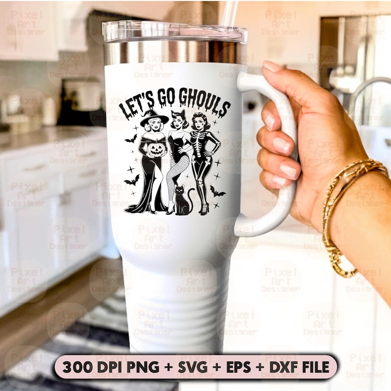 May include: White travel mug with a silver lid and handle. The mug features the text "LET'S GO GHOULS" above a graphic of three women in Halloween costumes, with bats and crosses. A hand holds the mug.
