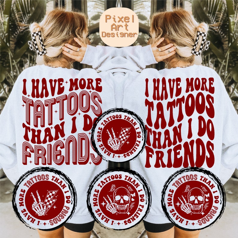 May include: White sweatshirt with red text that reads "I have more tattoos than I do friends". The text is in a retro font style. There are three circular designs on the sweatshirt, each with a skull and crossbones and the text "I have more tattoos than I do friends".