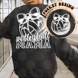 Może przedstawiać: Czarna bluza z białym nadrukiem piłki siatkowej i tekstem "Volleyball Mama" na plecach. Piłka siatkowa ma kokardkę na g&oacute;rze.