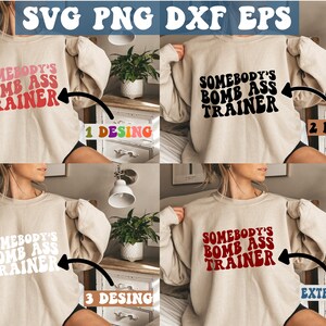 May include: Four images of a beige sweatshirt with the text "Somebody's Bomb Ass Trainer" in different colors. The text is in a retro font style. The first image has pink text, the second has black text, the third has white text, and the fourth has red text.