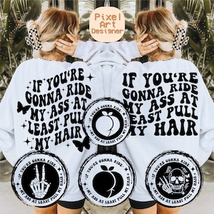 Könnte beinhalten: Weißes Sweatshirt mit dem Text "IF YOU'RE GONNA RIDE MY ASS AT LEAST PULL MY HAIR" in einem Retro-Schriftstil. Das Design umfasst Schmetterlingsgrafiken und kreisförmige Grafiken mit ähnlichem Text und anderen Bildern.
