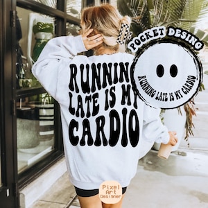 Pode incluir: Camisola branca com texto preto que diz "Running late is my cardio" em uma fonte retrô. O texto é cercado por um círculo preto com o mesmo texto em uma fonte menor.