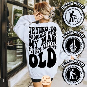 May include: White sweatshirt with black text that reads "Trying to grow old with my man but he's already old". The text is in a retro font. There are three pocket designs with different graphics, each with the text "Trying to grow old with my man but he's already old".