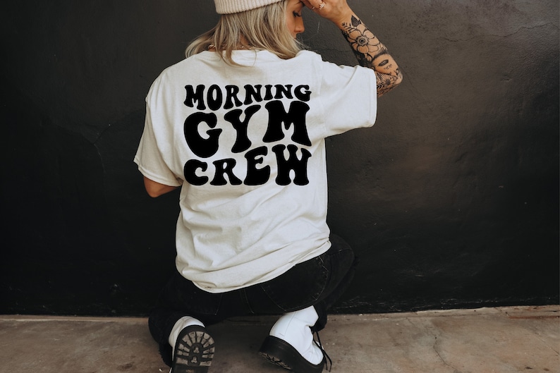 May include: A white t-shirt with black text that reads "Morning Gym Crew" in a retro font.