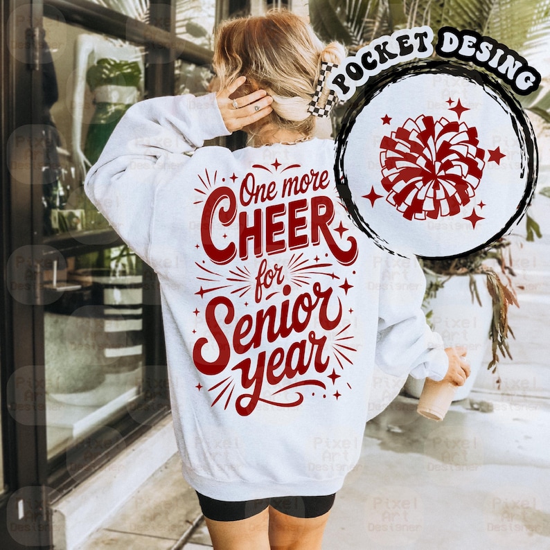 May include: A white sweatshirt with the text "One more CHEER for Senior Year" in red script. A red and white pom-pom graphic is on the upper right. The sweatshirt is a casual style.