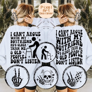 May include: White sweatshirt with black text that reads "I can't argue with my boyfriend he's older than me & old people don't listen". The text is in a retro font style. The sweatshirt has four black and white graphic designs on the front.