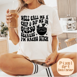 May include: Cream-colored t-shirt with a black graphic that reads "WELL CALL ME A CHIP & DIP ME IN QUESO BECAUSE I'M NACHO BITCH." The design includes a bowl of queso with chips. The shirt is a casual style.